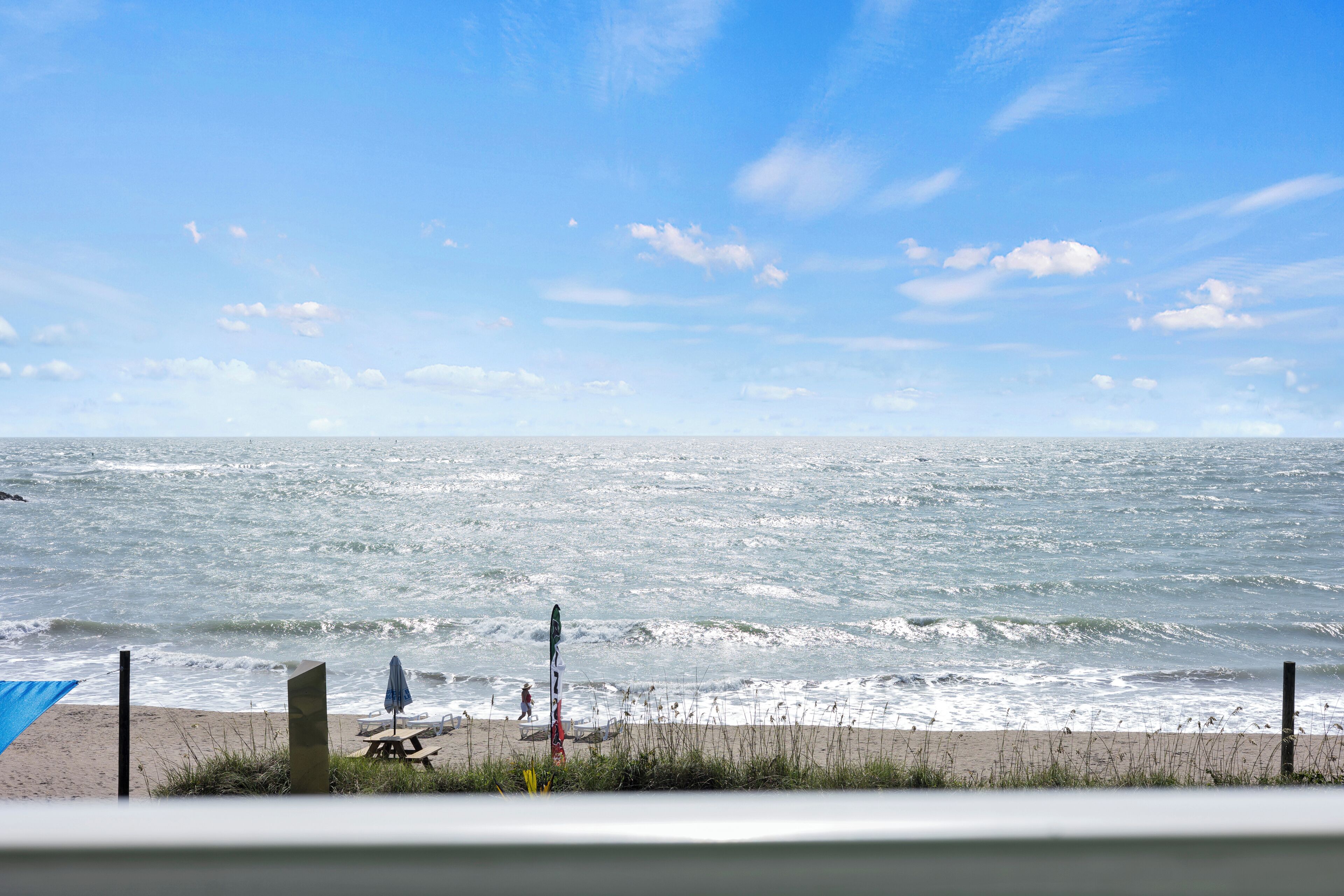 A beach with a clear sky, waves, and a picnic table.