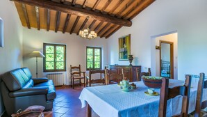 Un coin repas avec une table dressée pour quatre personnes, des chaises en bois, un canapé et une lampe.