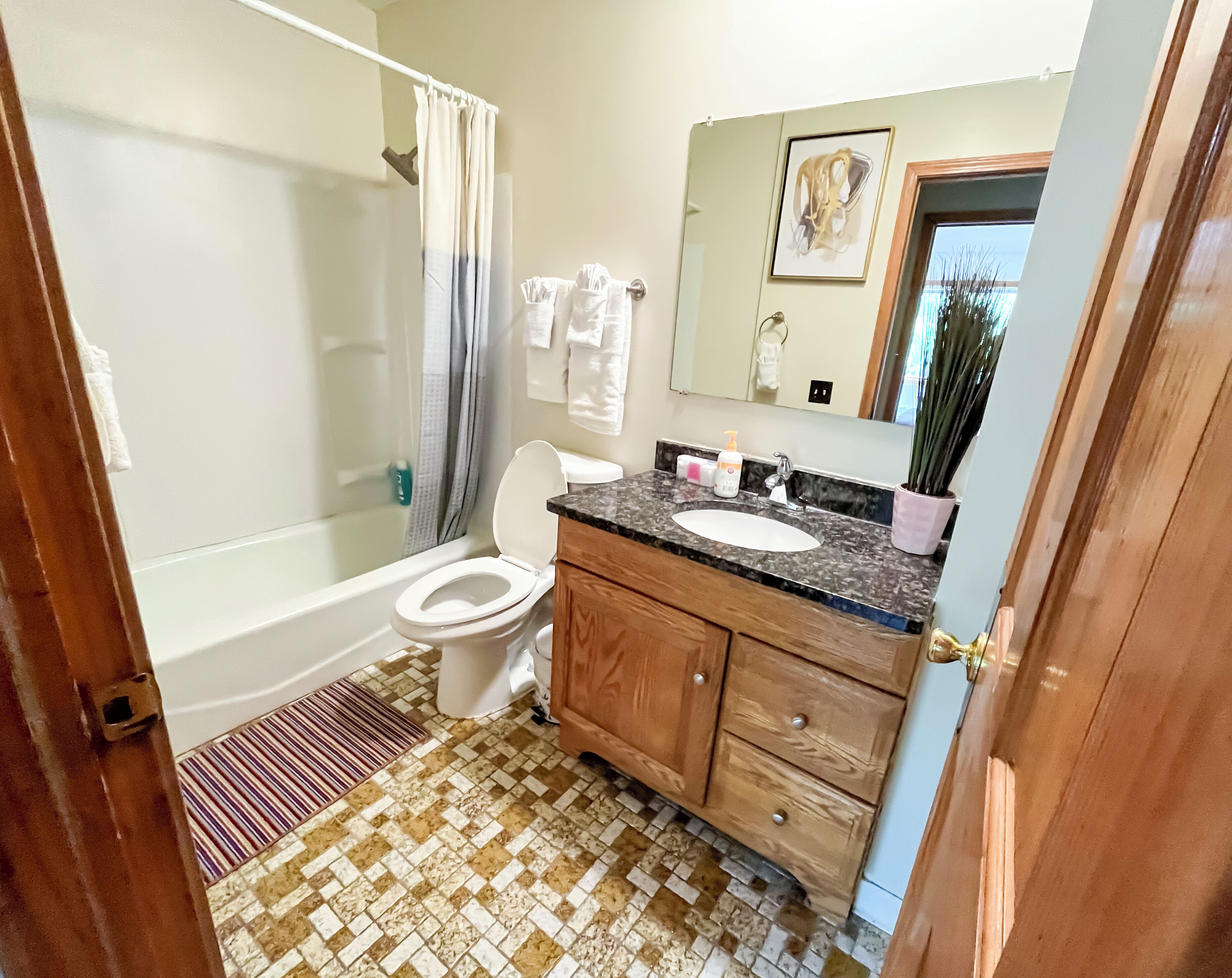 A bathroom with a bathtub, toilet, sink, and a shower area.