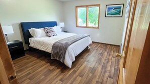Une chambre à coucher avec un lit, des tables de chevet, une fenêtre et un tableau au mur.