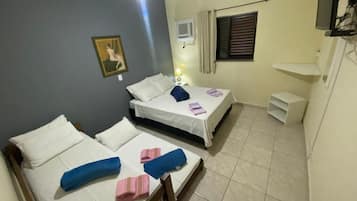 Quarto de hotel com duas camas, uma pequena mesa, televisão e janela com cortinas.
