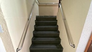 Una escalera con barandilla, un tapete con el texto "BEM-VINDO" y una pared con un cuadro.
