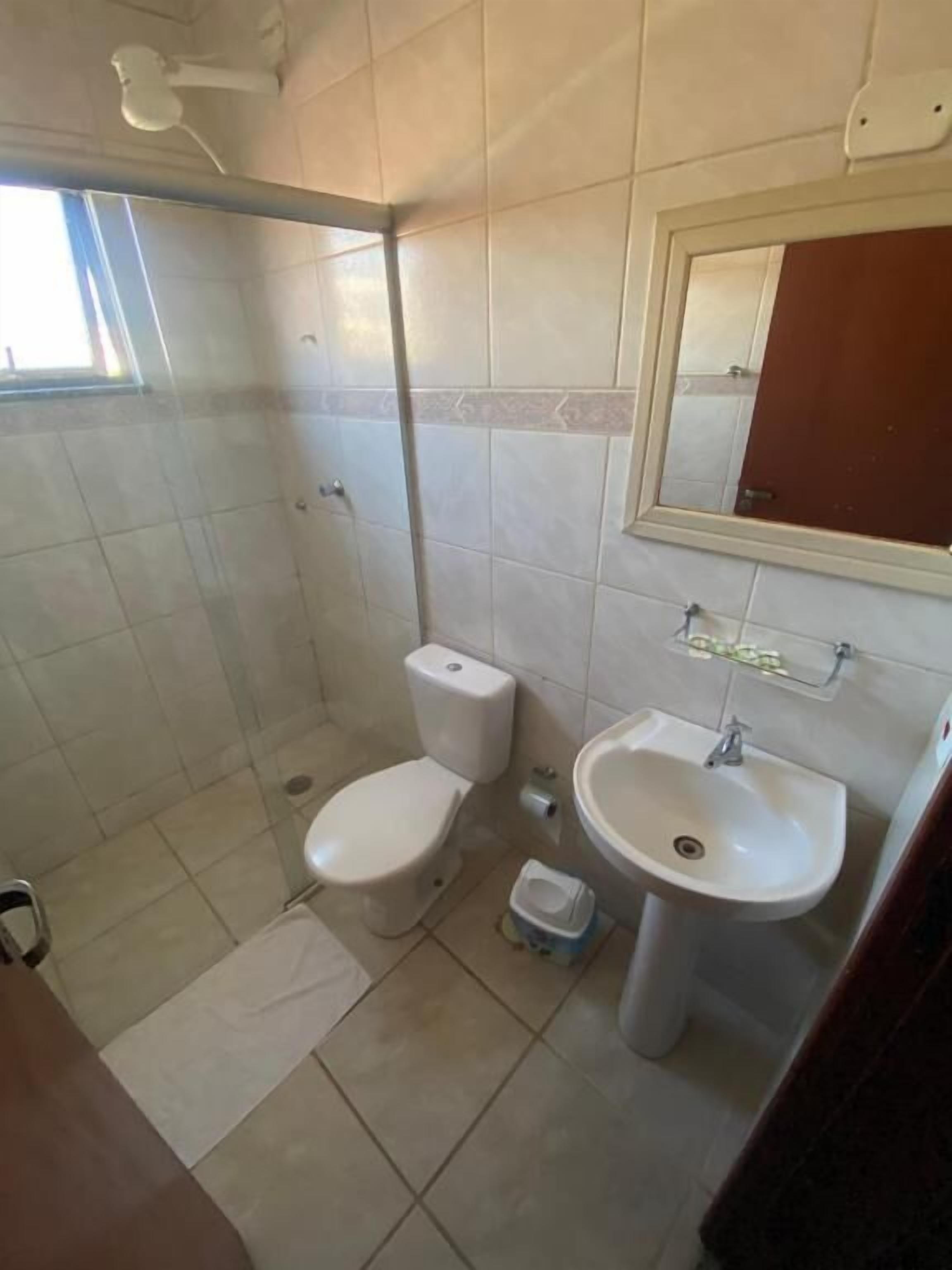 A bathroom with a toilet, sink, and shower.