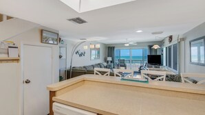 Eine moderne Küche mit Geschirrspüler, ein Essbereich mit Tisch und Stühlen sowie ein Wohnzimmer mit Sofa und Fernseher.