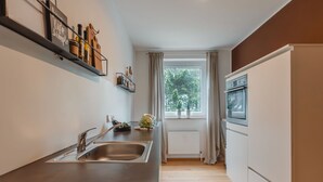 Una cocina moderna con un lavamanos de acero inoxidable, un horno empotrado y una ventana con cortinas.