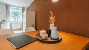 Un comedor moderno con una mesa de madera, una carpeta negra, jarrones decorativos y una planta en maceta.