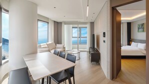 A modern hotel room with a dining area, a sofa, a TV, and a bed. - NewCZ Haeundae Residence (Busan)