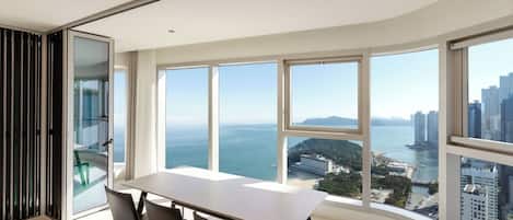 Habitación moderna con un ventanal grande que ofrece vistas a un horizonte urbano y una masa de agua.