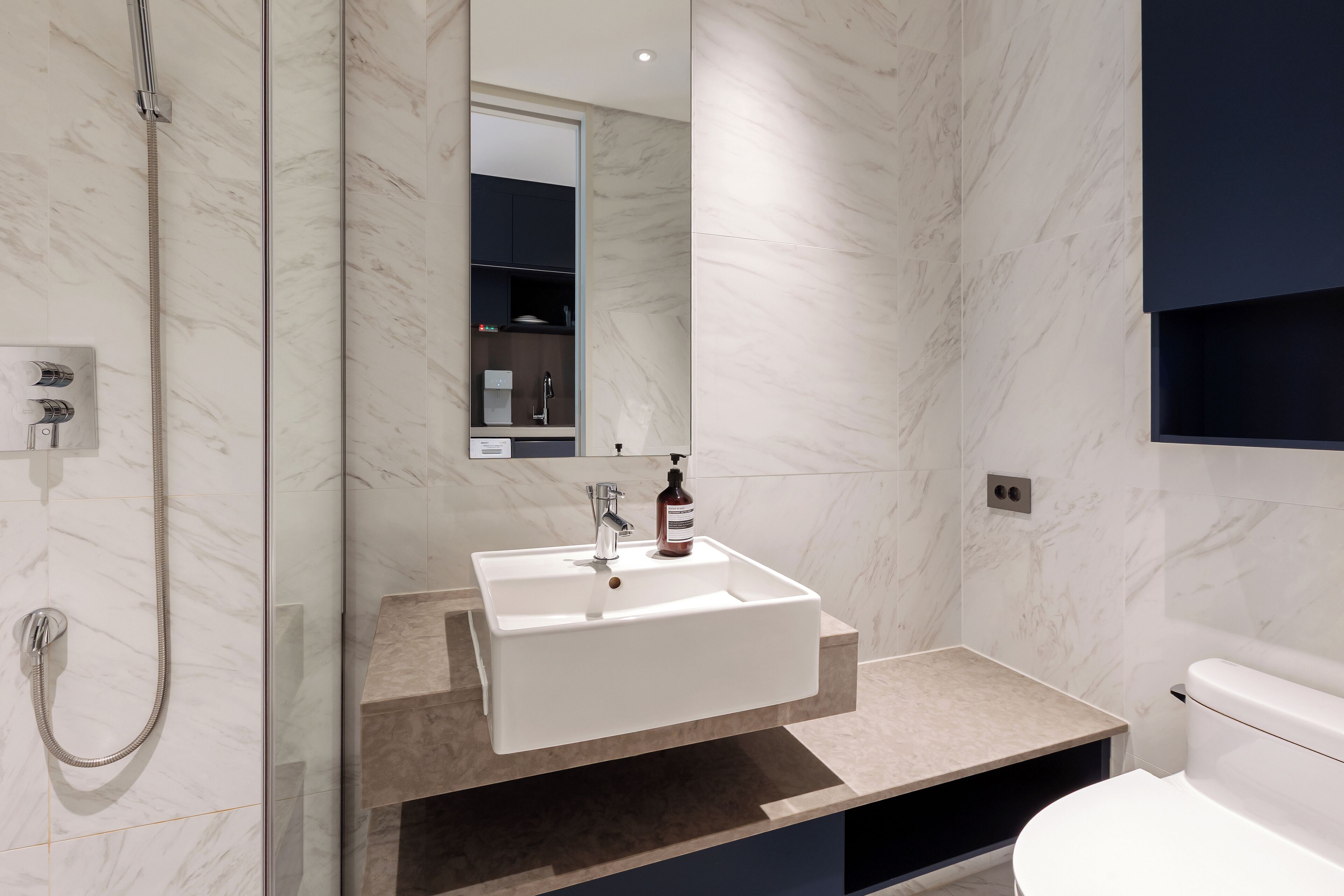 Une salle de bain moderne avec un lavabo blanc, une douchette à main et des toilettes.