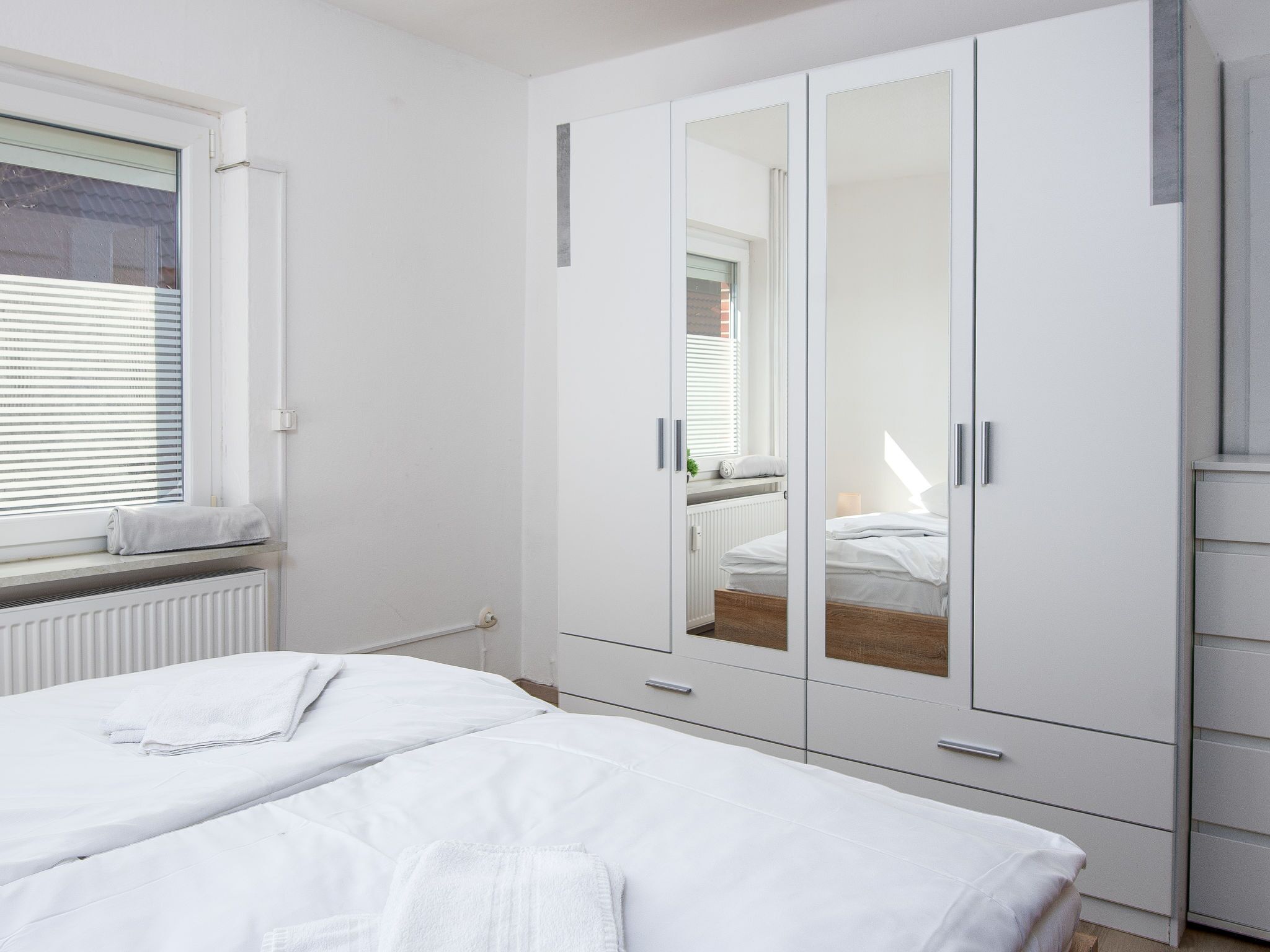 Un dormitorio con cama, armario y ventana con persianas.
