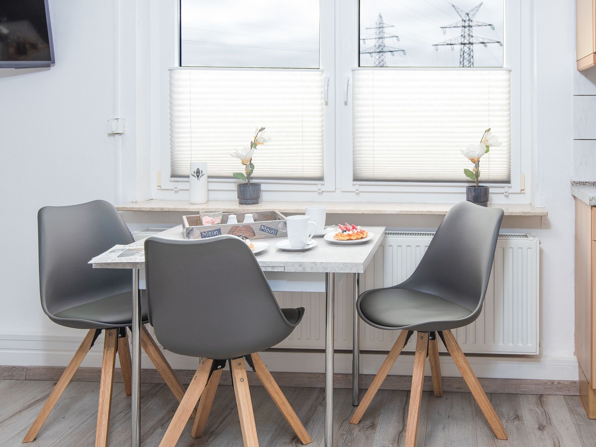 Ein Essbereich mit Tisch, Stühlen und einem Fenster mit Jalousien.