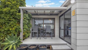 A modern building with a covered patio area, a number '6' on the side, and potted plants on the ground.