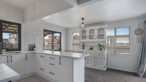 A modern kitchen with white cabinetry, a large island, and a view of the outside.
