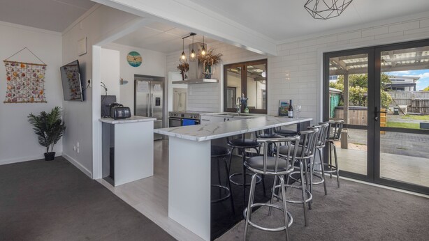 A modern kitchen with a large island, bar stools, and a view to the outdoors.