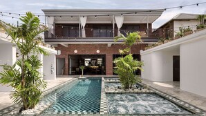 Een modern huis met een zwembad, een overdekt terras en een balkon met lichtjes.