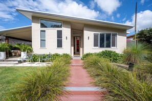 A modern two-story house with a covered patio, a red pathway leading to the entrance, and a well-maintained garden with various plants. - Brunswick Lux - Close to Creek & Beach (Brunswick Heads)