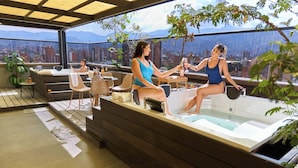 A rooftop terrace with a hot tub, seating area, and a city view. - Rosa Negra Stadio | Your Cozy Getaway (Medellín)