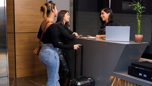 En receptionsdisk med en bärbar dator, en växt och en resväska.
