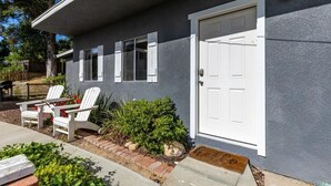 A house with a white door, a small porch with two white Adirondack chairs, and a mailbox.