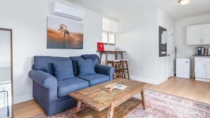 A living room with a blue sofa, a wooden coffee table, and a painting on the wall.