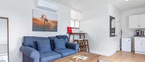 A living room with a blue sofa, a wooden coffee table, and a painting on the wall.