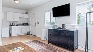 A modern kitchen with white cabinets, a black TV, and a large window.