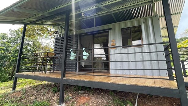 Un bâtiment moderne à la structure métallique, doté d’un porche couvert et d’une terrasse en bois.