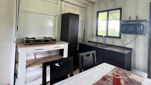 Une cuisine compacte équipée d’un four à micro-ondes, d’un petit réfrigérateur et d’une table en bois avec des chaises.