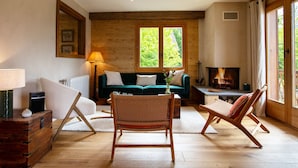 Ein gemütliches Wohnzimmer mit Holzboden, einem grünen Sofa, einem Korbstuhl und einem Kamin.