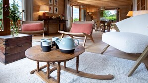 Ein gemütliches Zimmer mit Holzmöbeln, einem runden Tisch mit Teekannen und einem Schaukelstuhl.