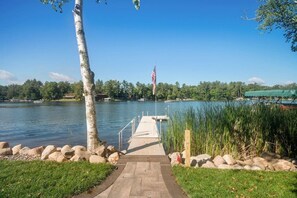 Muelles sobre el lago con una bandera, rodeado de rocas y césped.