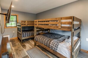 A bunk bed room with a desk and a window.