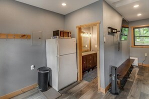 A compact kitchen with a refrigerator, a microwave, and a sink with wooden cabinets.