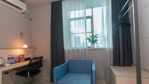 A small, modern room with a desk, chair, and a window with curtains. - StarChain Qijiang Hotel - Zhongshan Xingzhong Square Sunwen Pedestrian Street Branch  (Zhongshan)