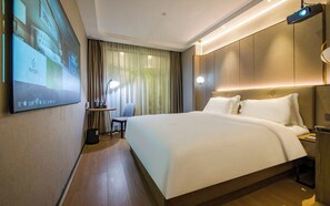 A hotel room with a large bed, a desk with a chair, a TV screen, and a projector. - StarChain Shenzhen Bay Hotel (Shenzhen Bay Port Branch) (Shenzhen)