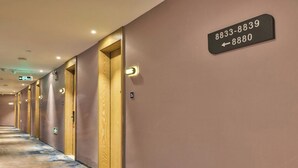 A hotel hallway with numbered doors, a carpeted floor, and a wall-mounted sign indicating room numbers. - StarChain Shenzhen Bay Hotel (Shenzhen Bay Port Branch) (Shenzhen)