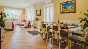 Un'area pranzo con un tavolo apparecchiato per quattro persone, sedie, un quadro appeso e una finestra con tende.