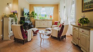 Un soggiorno accogliente con un pianoforte, posti a sedere comodi, un tavolo da pranzo e vista sul panorama esterno.