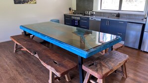 Una cocina con mesa de vidrio, bancos de madera y electrodomésticos modernos.