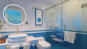 A bathroom with a large oval mirror, a sink, a toilet, and a glass-enclosed shower area. - StarChain Ocean View Hotel (Shenzhen Yantian Seafood Street) (Shenzhen)