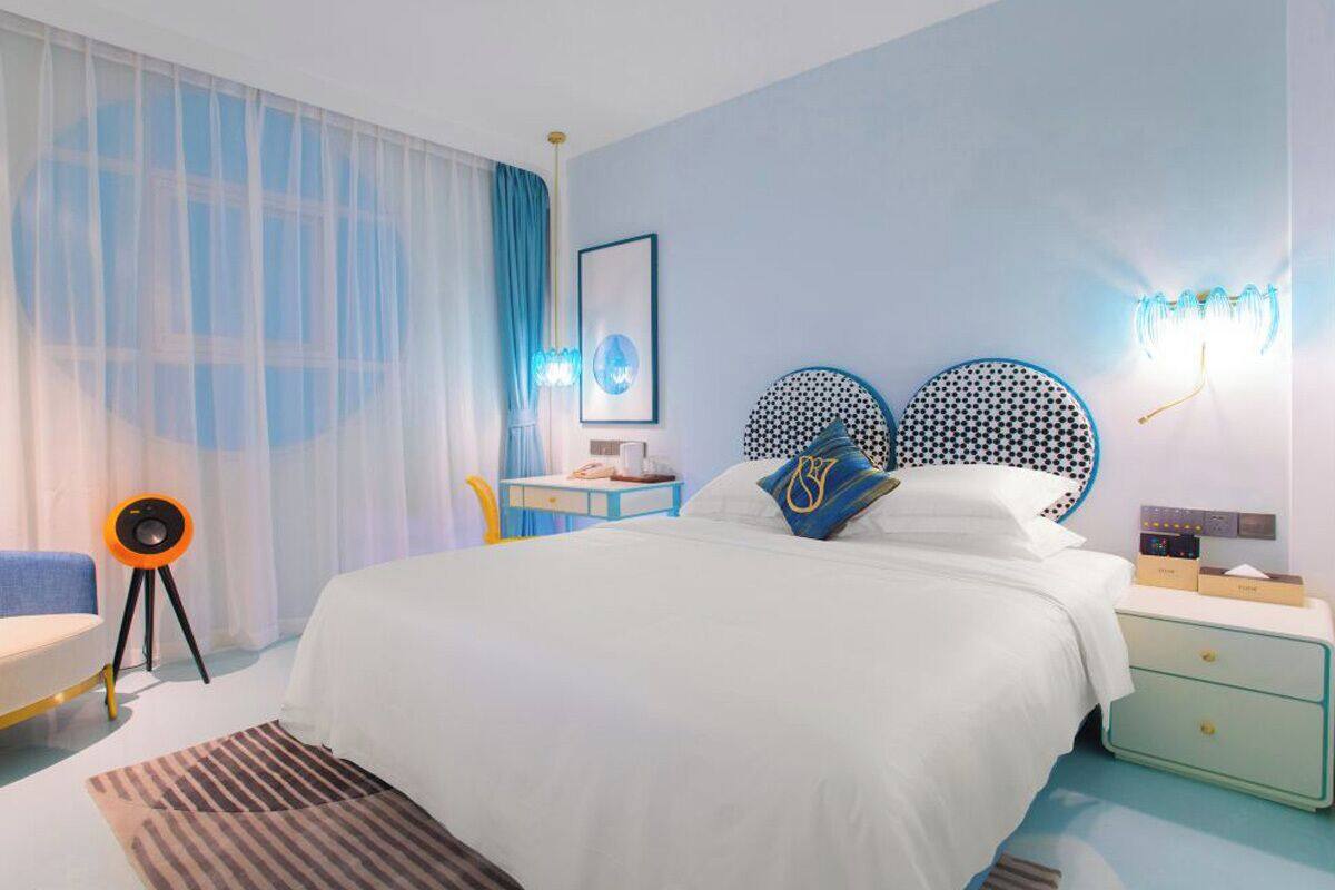 A modern bedroom with a large bed, a bedside table, a chair, and a desk.