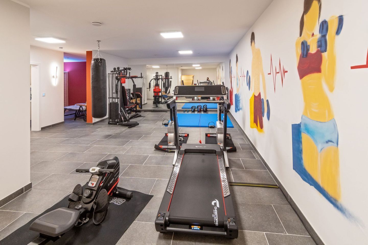 A gym with treadmills, weight machines, and a punching bag.