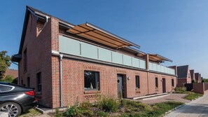 A modern brick building with a flat roof, large windows, and a car parked in front. - Arngast 5-Star Vacation Home with Sauna and Pool in Norddeich - Exclusive 5-Star Home (Norden)