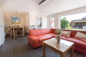 En moderne stue med en rød sofa, et træbord og et billede på væggen.