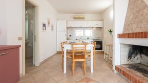 A modern kitchen with a dining area, a fireplace, and a red cabinet. - Sa vida by Interhome (Porto Corallo)