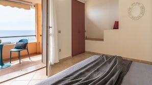 A bedroom with a bed, a chair, a small table, a wardrobe, and a view of the sea. - Sa vida by Interhome (Porto Corallo)