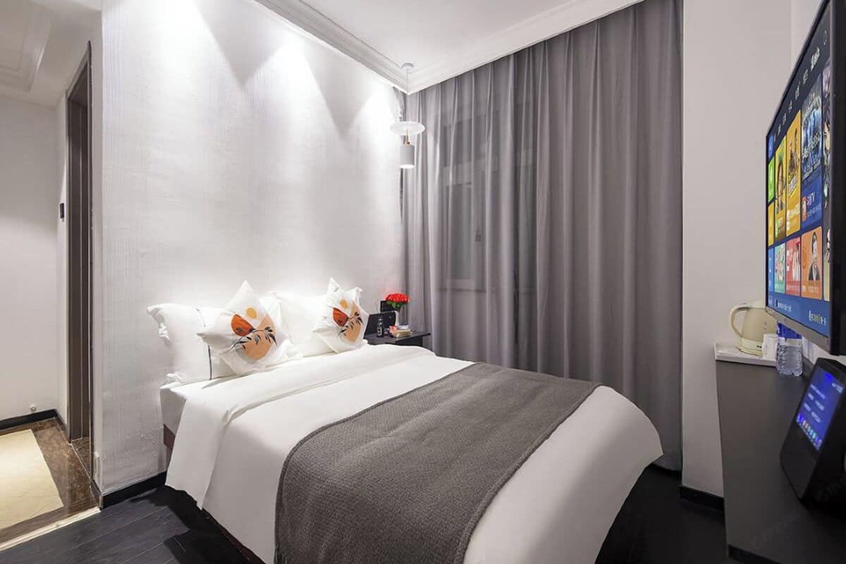 Habitación de hotel con una cama grande, un televisor de pantalla plana y un escritorio con una cafetera.