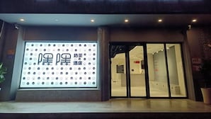 A hotel entrance with a neon sign and a large display of emoticons. - Starchain Heehee Hotel - Sanya Bay Walking Street Store (Sanya)