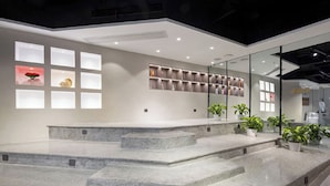 A modern interior with a central staircase, a glass wall with shelves, and potted plants. - Starchain Heehee Hotel - Sanya Bay Walking Street Store (Sanya)