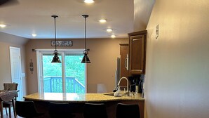 A kitchen with a bar area, wooden flooring, and a view of the outdoors.
